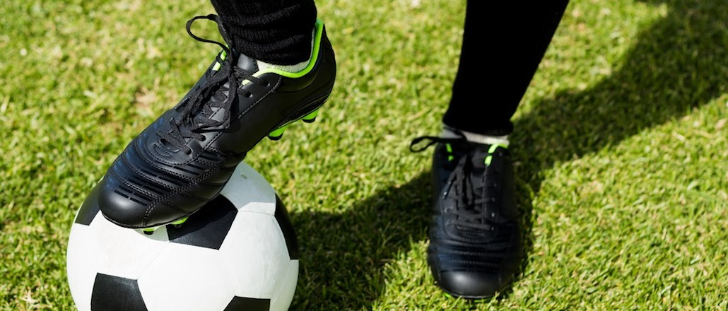 Female football player standing with her feet on ball